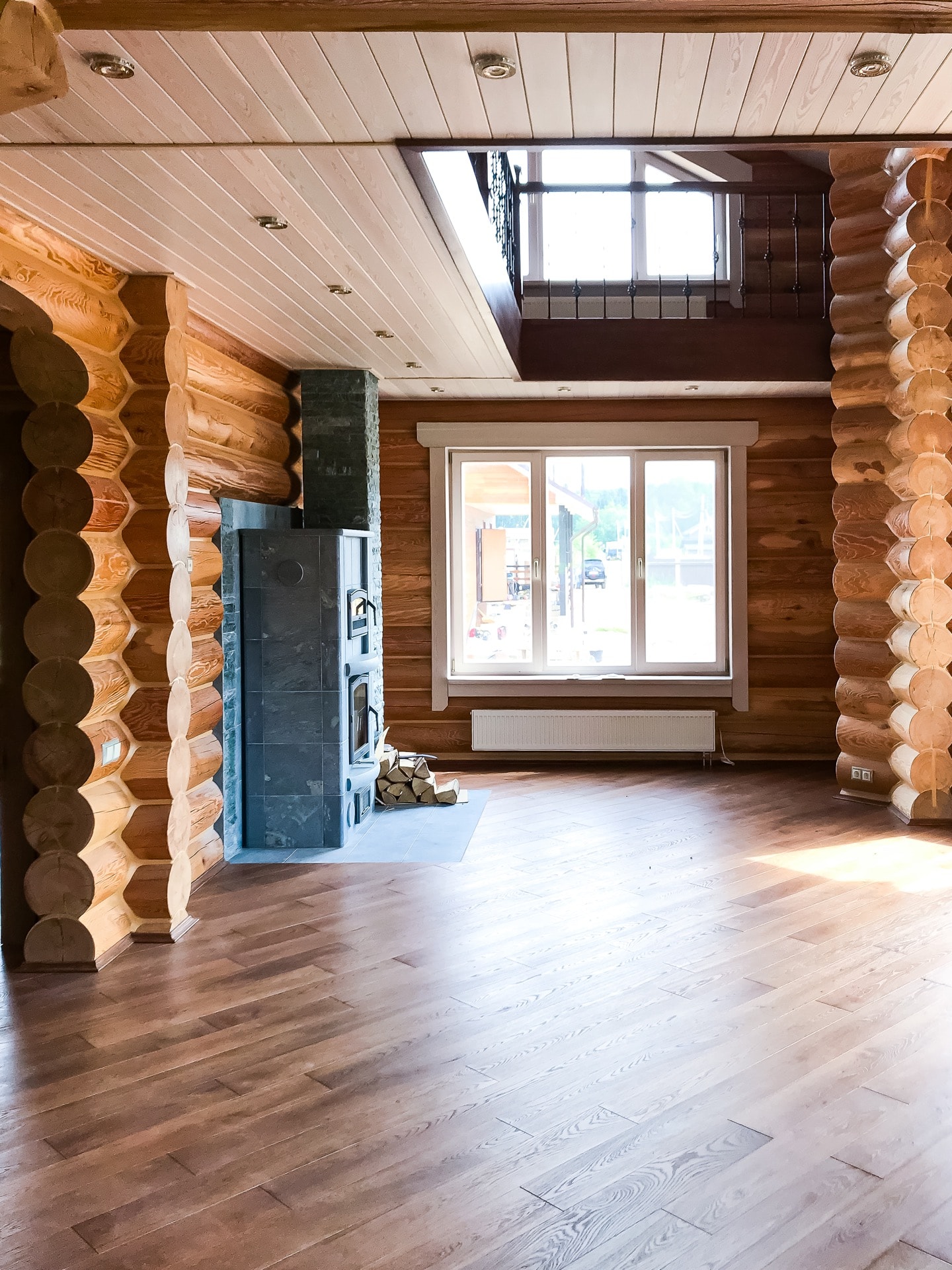 Внутренняя отделка первого этажа деревянного дома из оцилиндрованного бревна с камином и дымоходом.